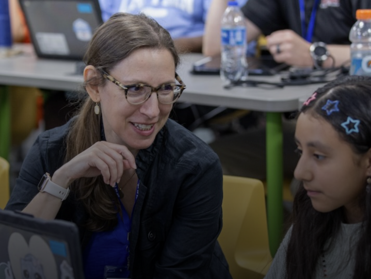 Dr. Maya Israel in a classroom, looking at a girl.